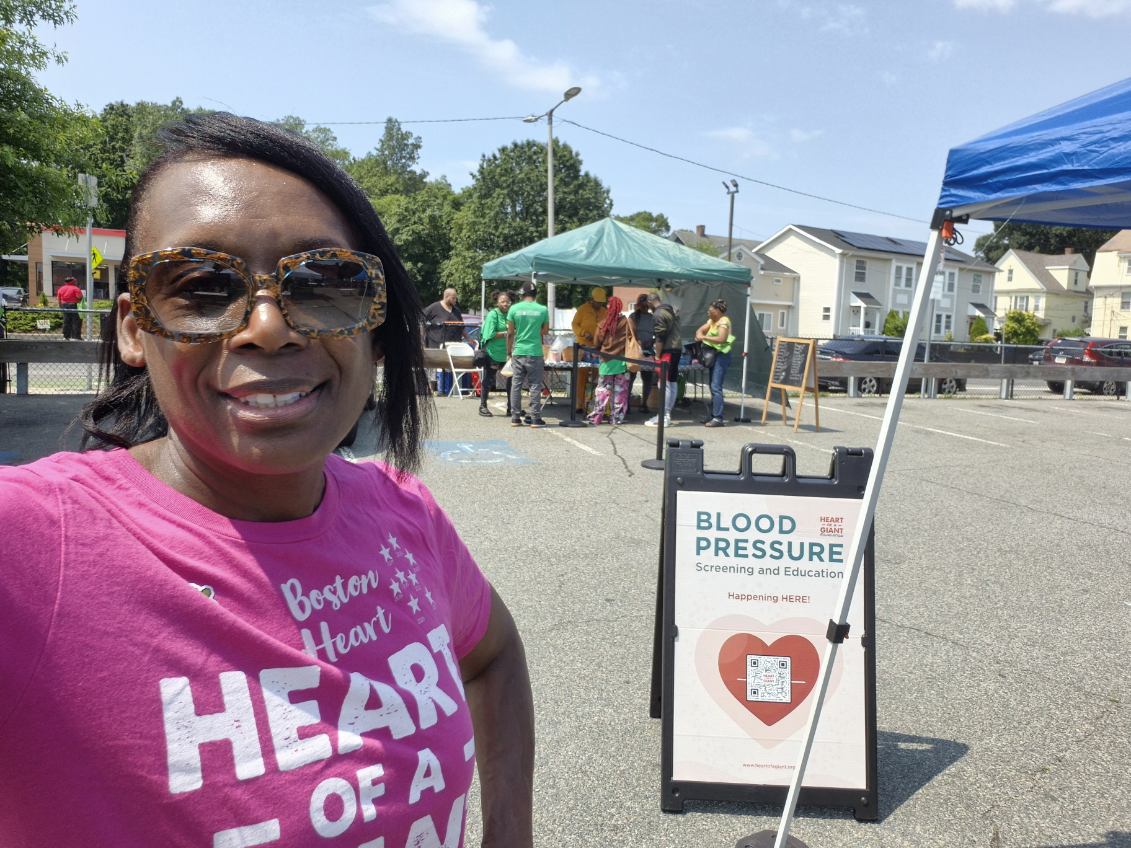 Community member selfie beside the Heart of a Giant blood pressure sign.